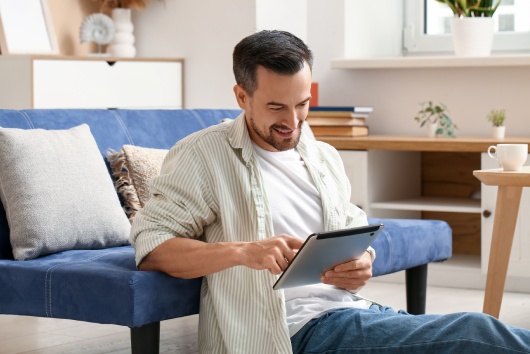 Handsome man using tablet computer on floor in living room