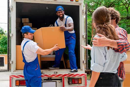 A man and woman load boxes into a moving truck, preparing for their move from San Diego to Charlotte.