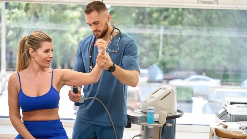 Skilled orthopedist performing trigger point therapy on female client forearm
